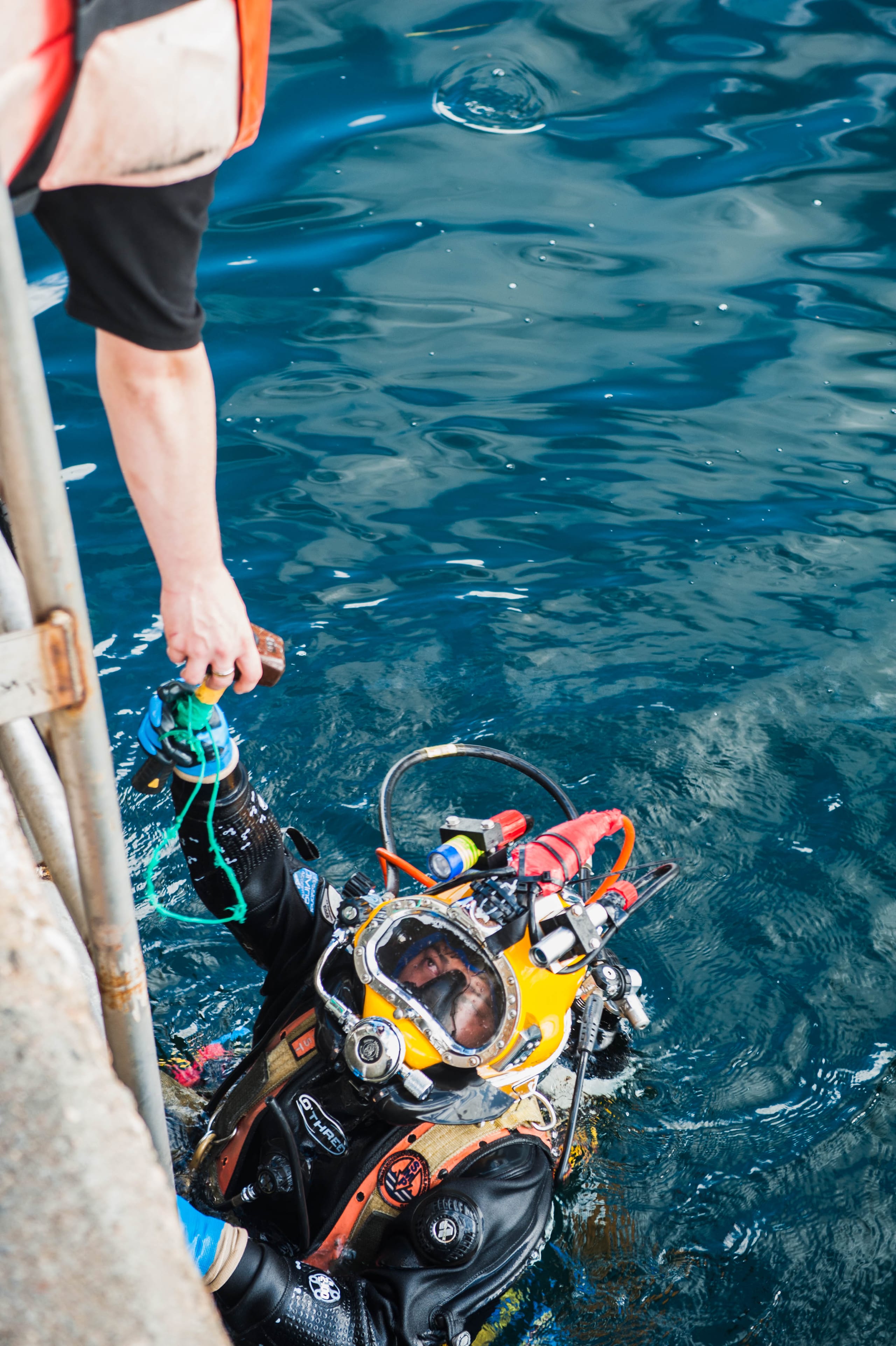 Commercial diver wearing a surface-supplied diving helmet entering the water.